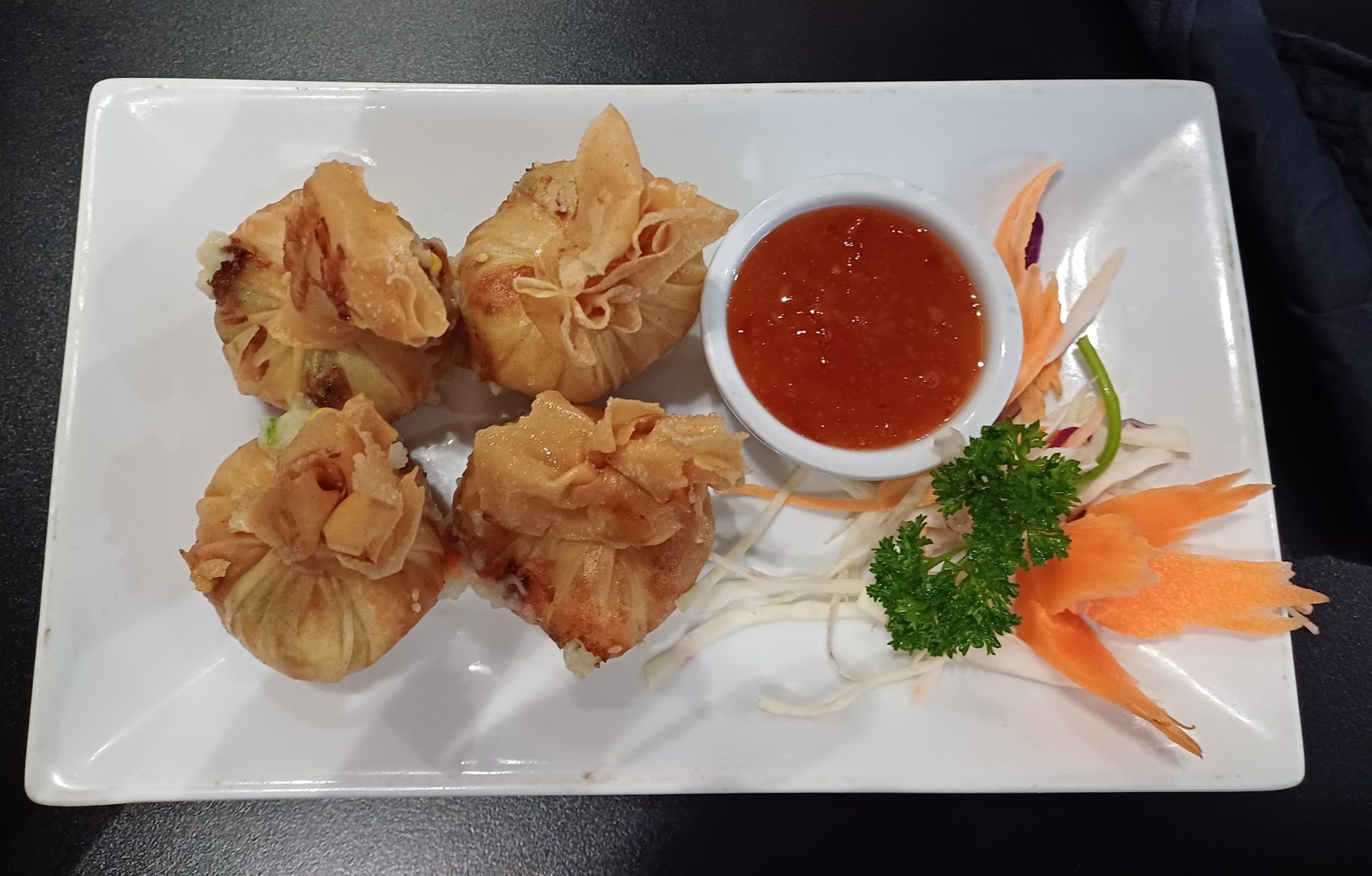 Fried parcels with a red dipping sauce and carved carrot garnish